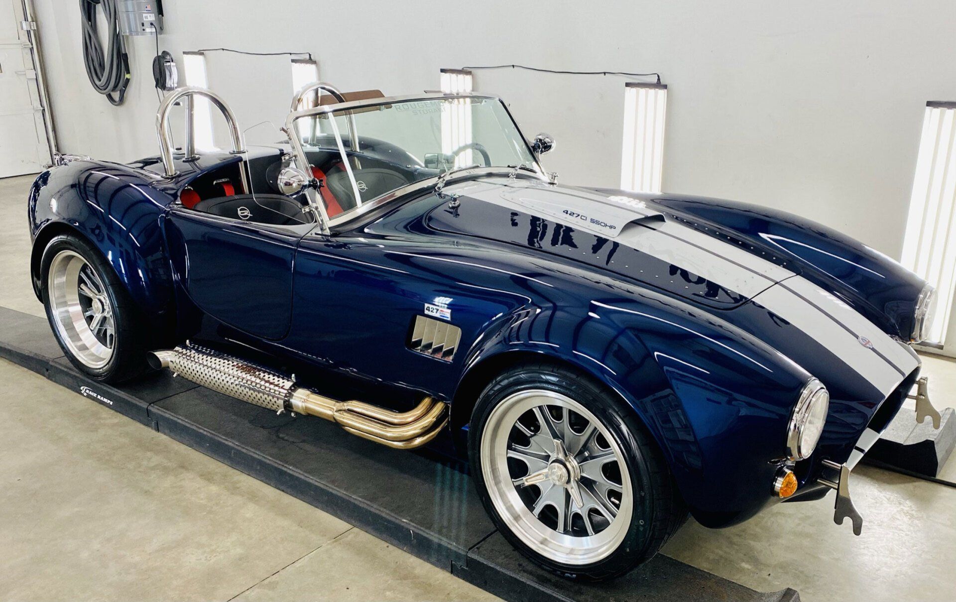 A blue and white sports car is parked in a garage.