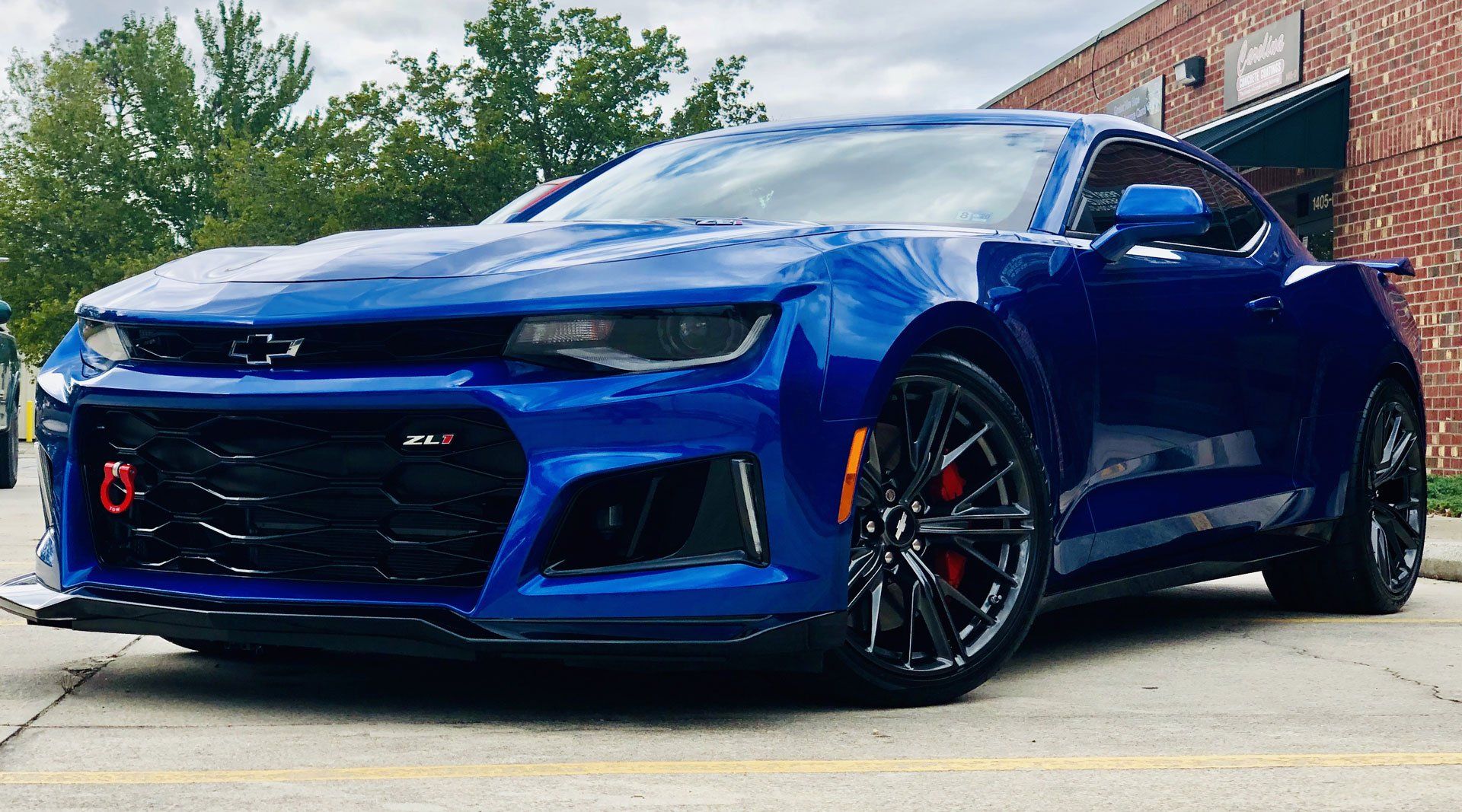 A blue chevrolet camaro zl1 is parked in front of a brick building.