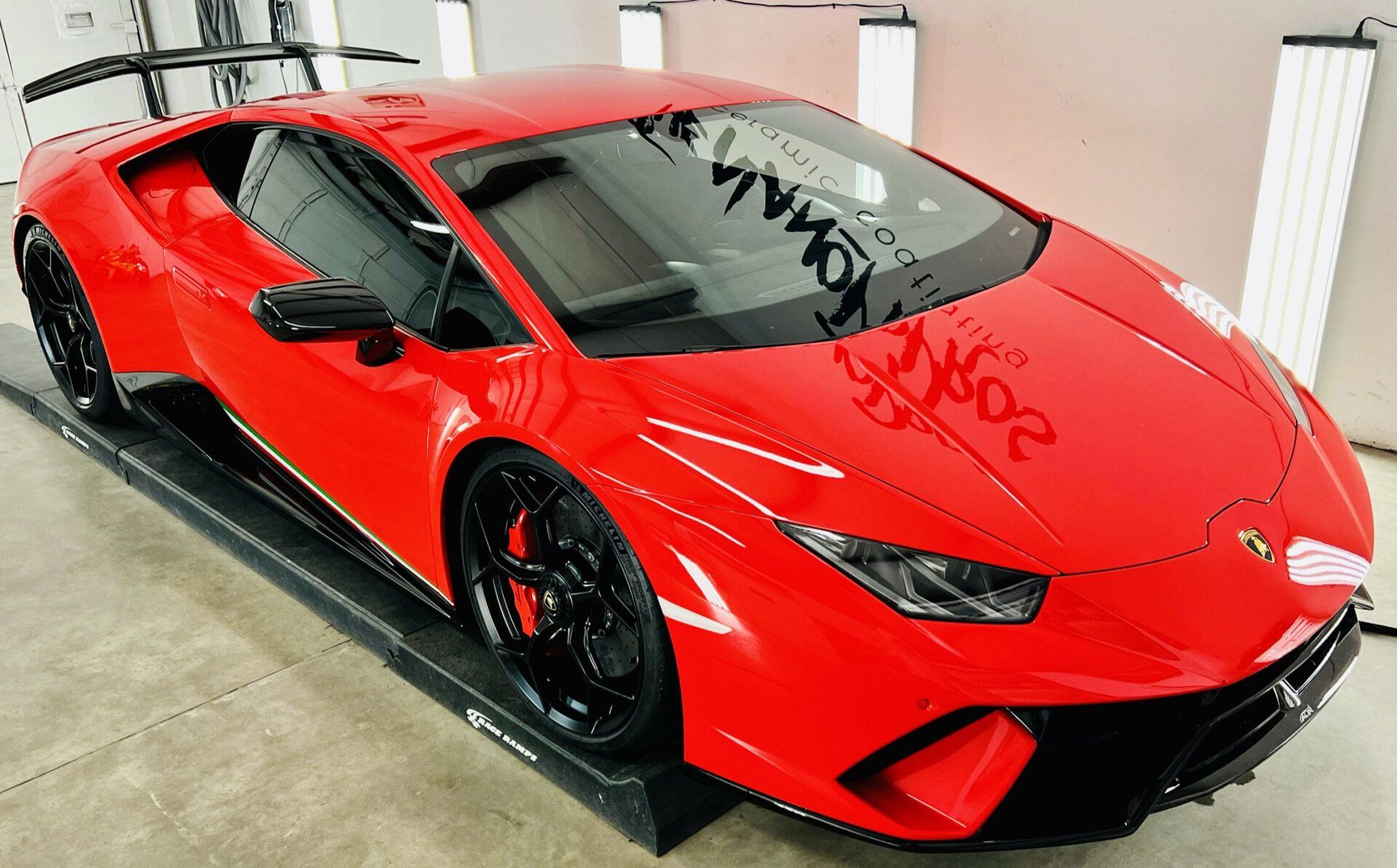 A red lamborghini huracan is parked on a ramp in a garage.