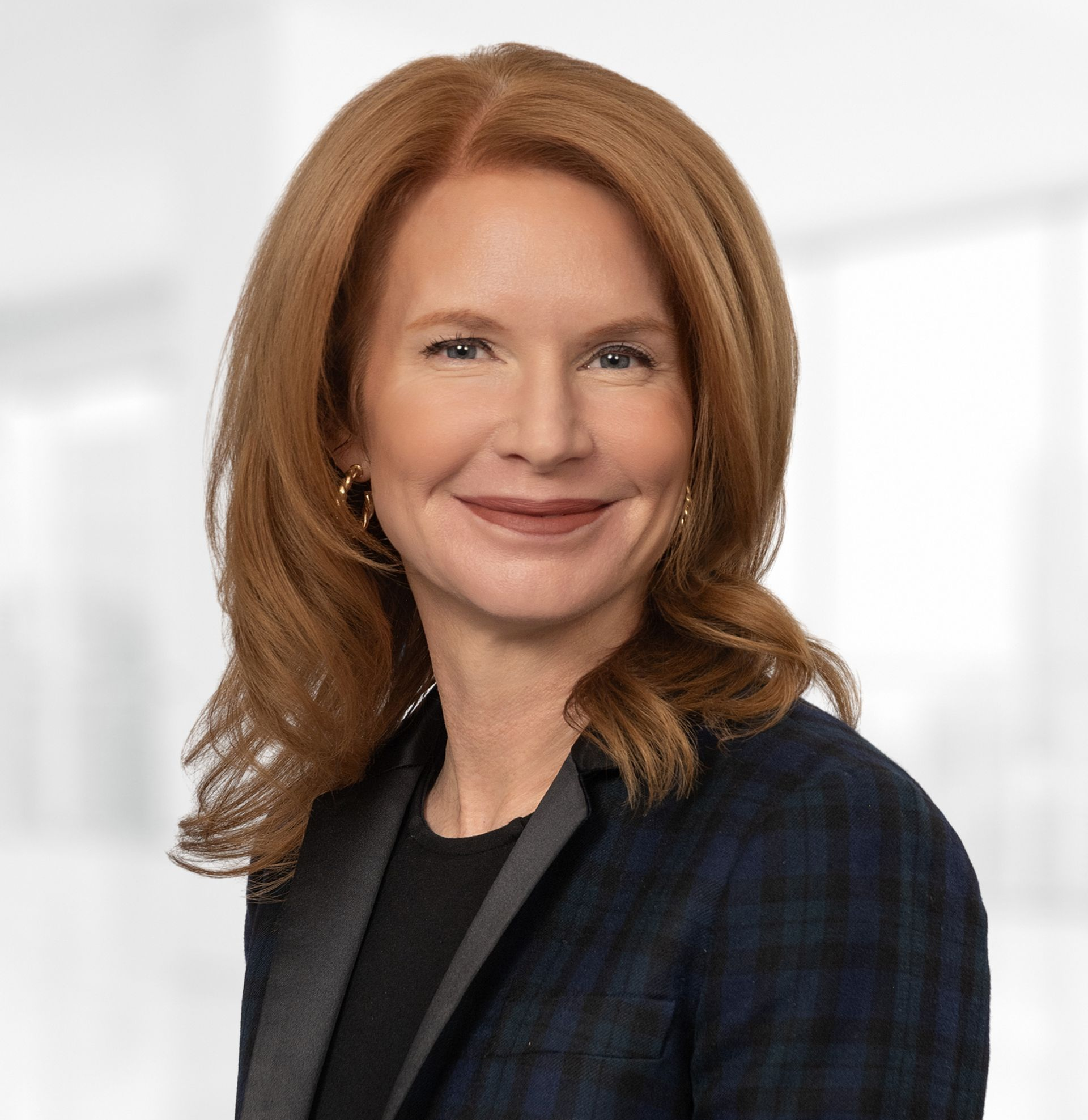 A woman with red hair is smiling and wearing a blue jacket