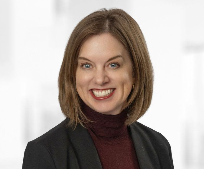 A woman in a black jacket is smiling for the camera.