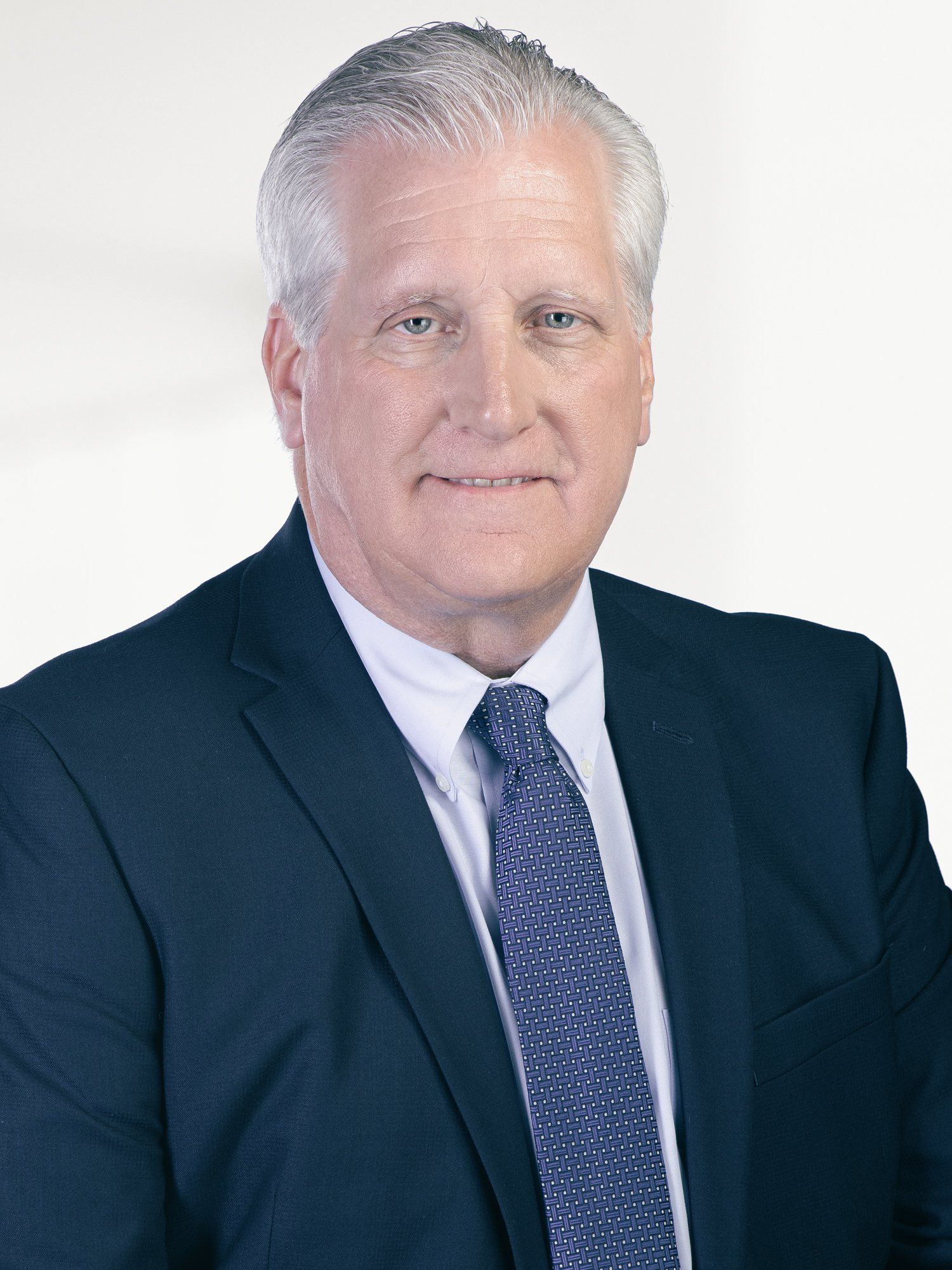 A man in a suit and tie is smiling for the camera