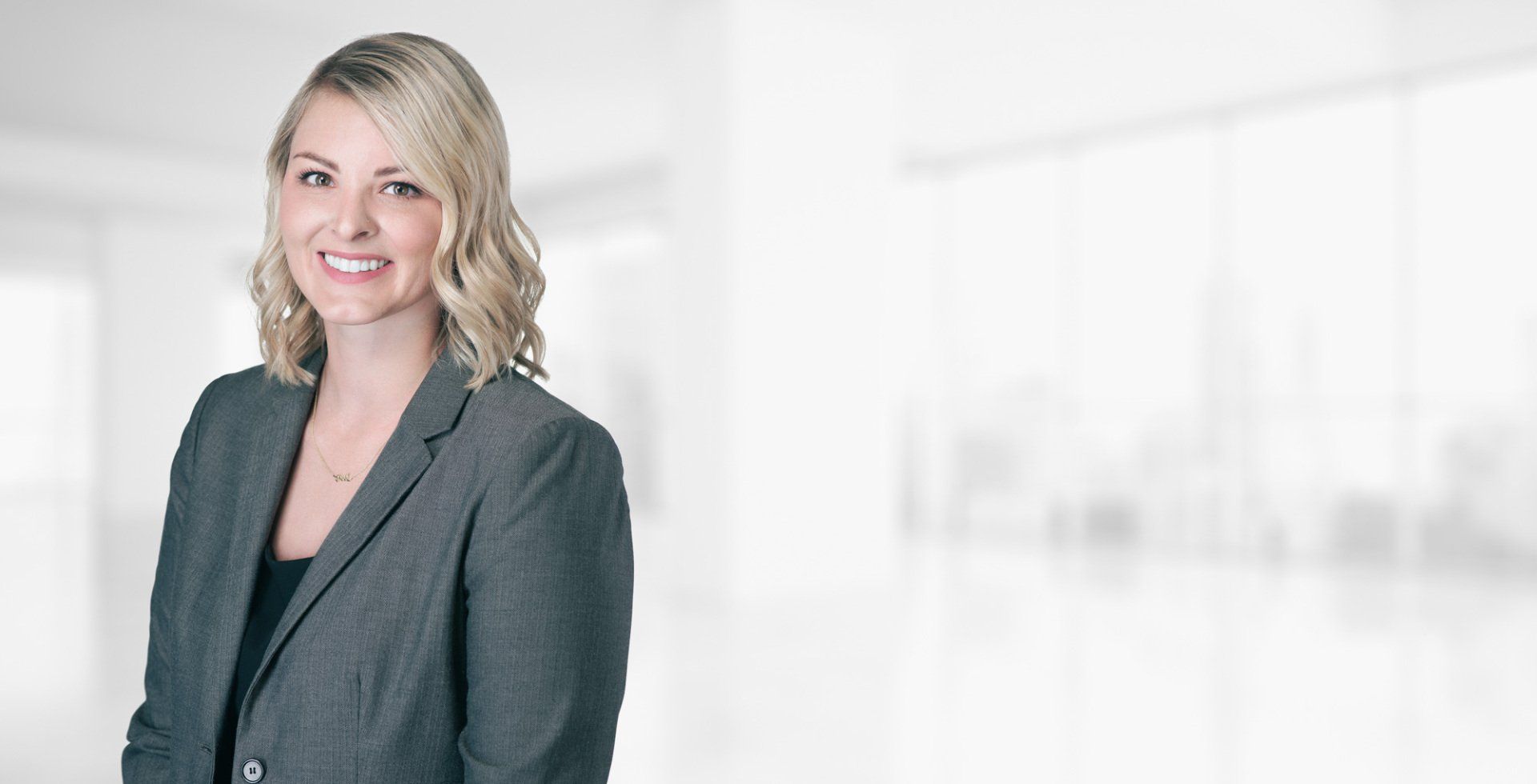 A woman in a suit is standing in a room and smiling.