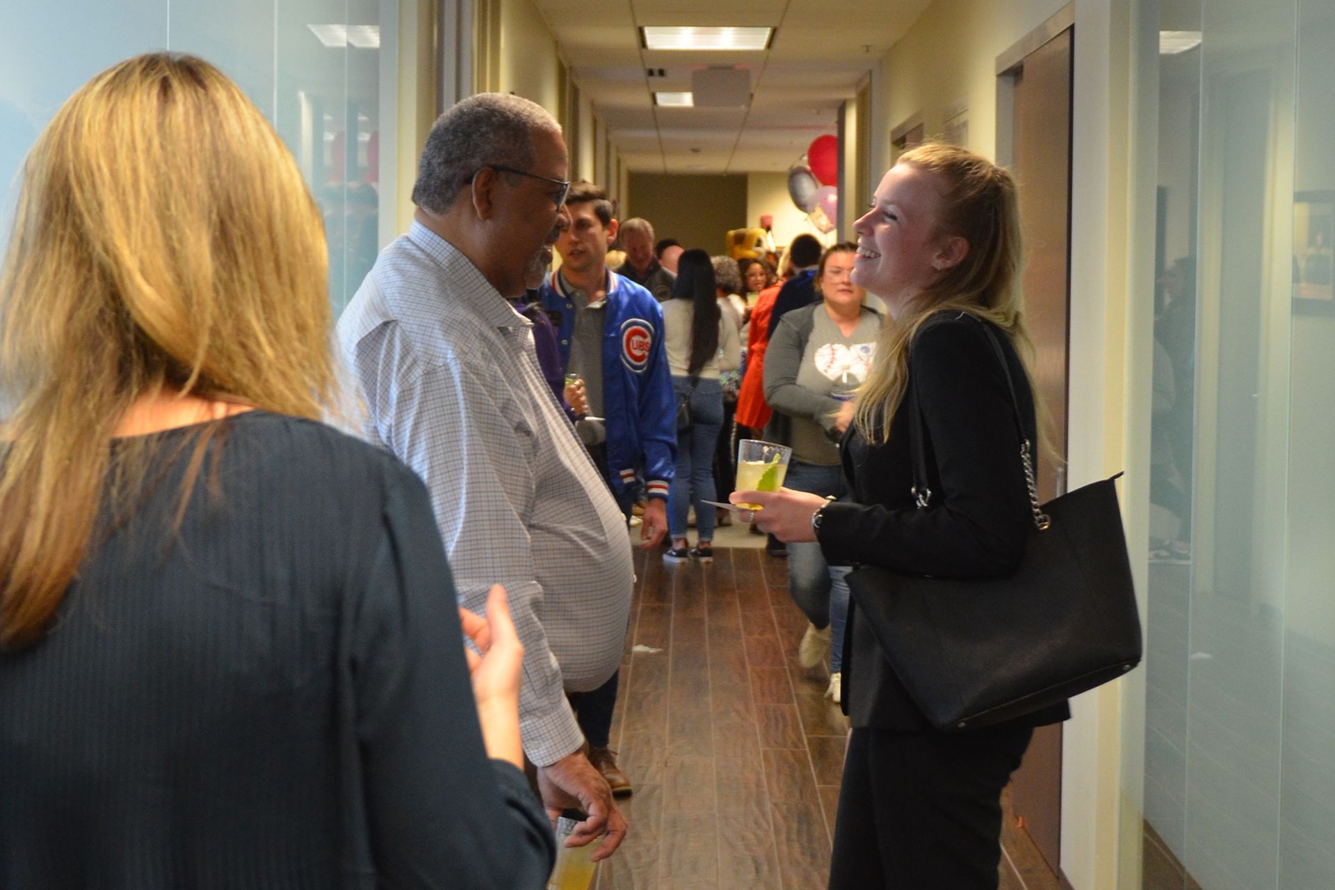 A group of people are standing in a hallway talking to each other.