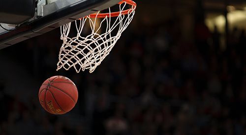 A basketball is going through the net of a basketball hoop.