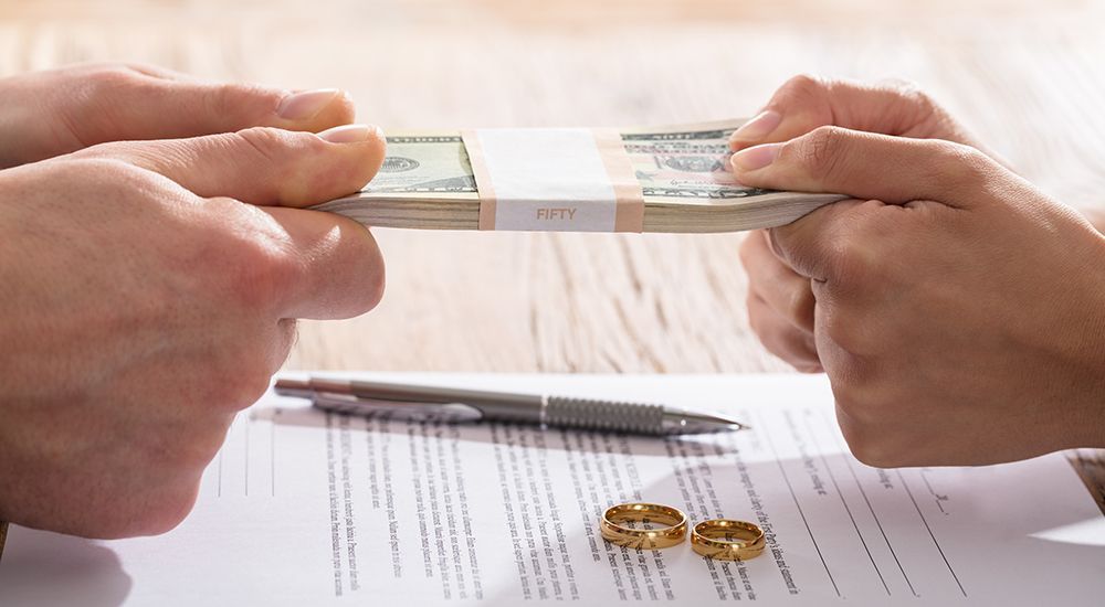 A man and a woman are holding a stack of money in their hands.