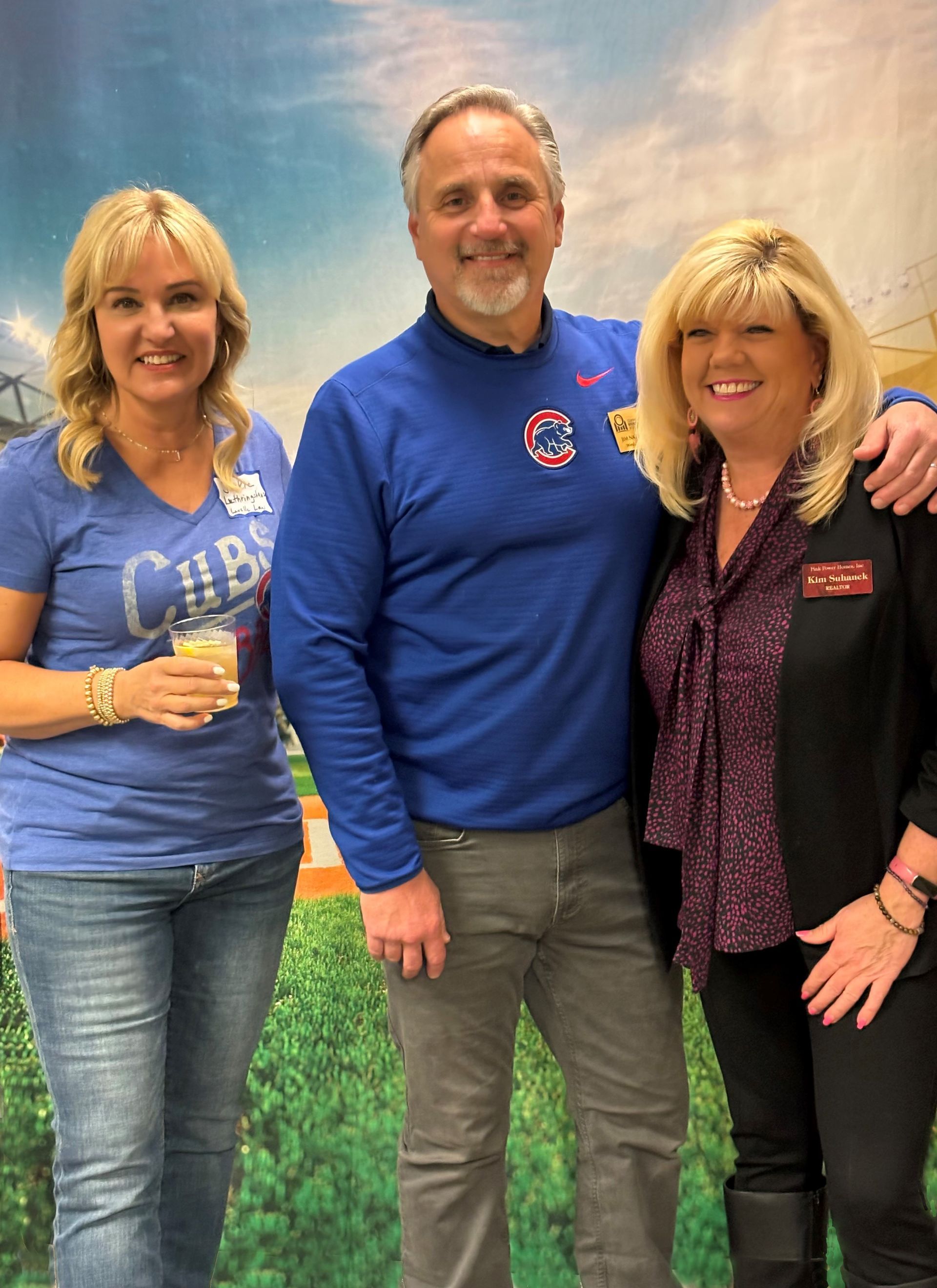 A man in a blue cubs shirt poses with two women