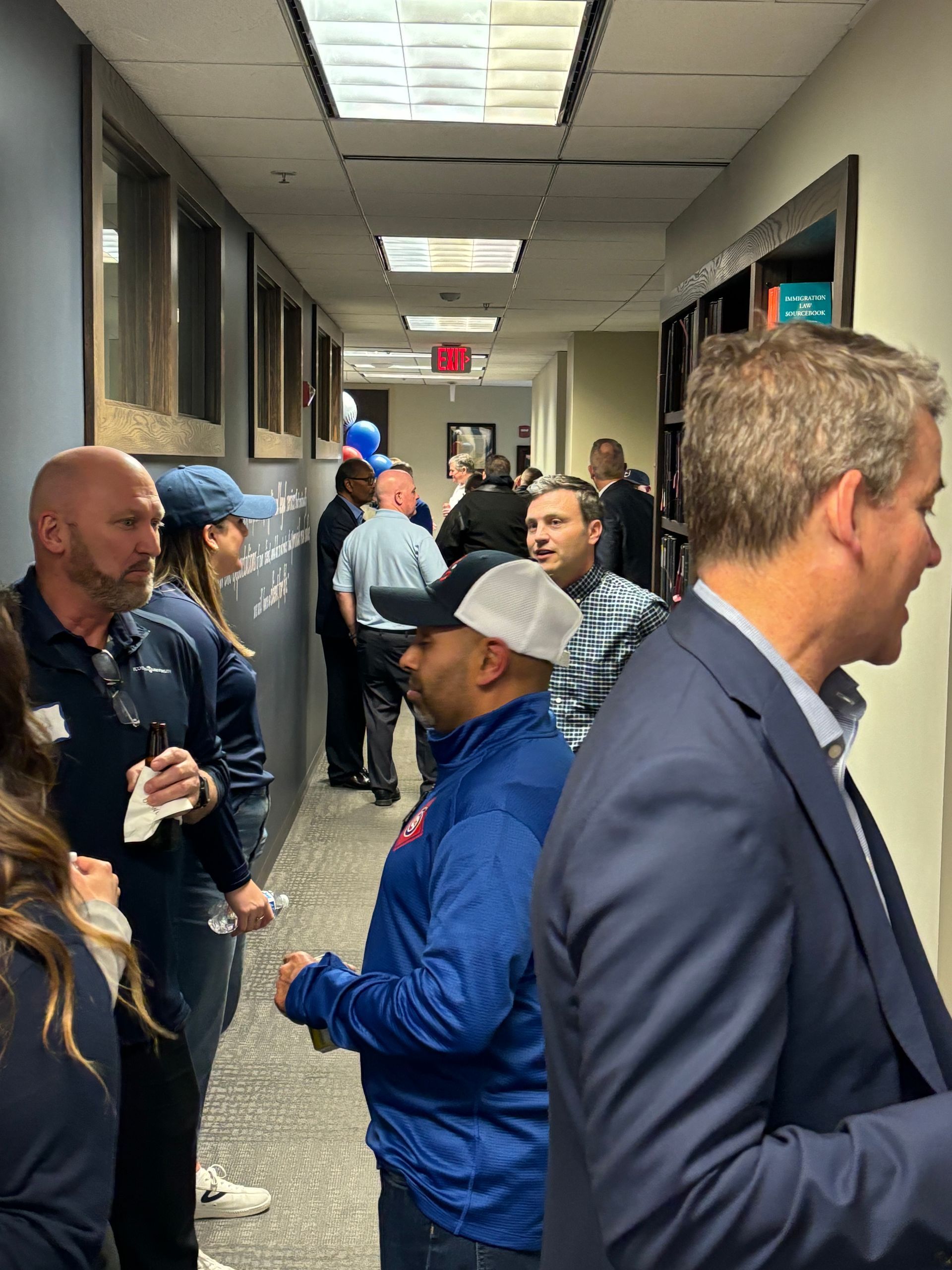 A group of people are standing in a hallway talking to each other.