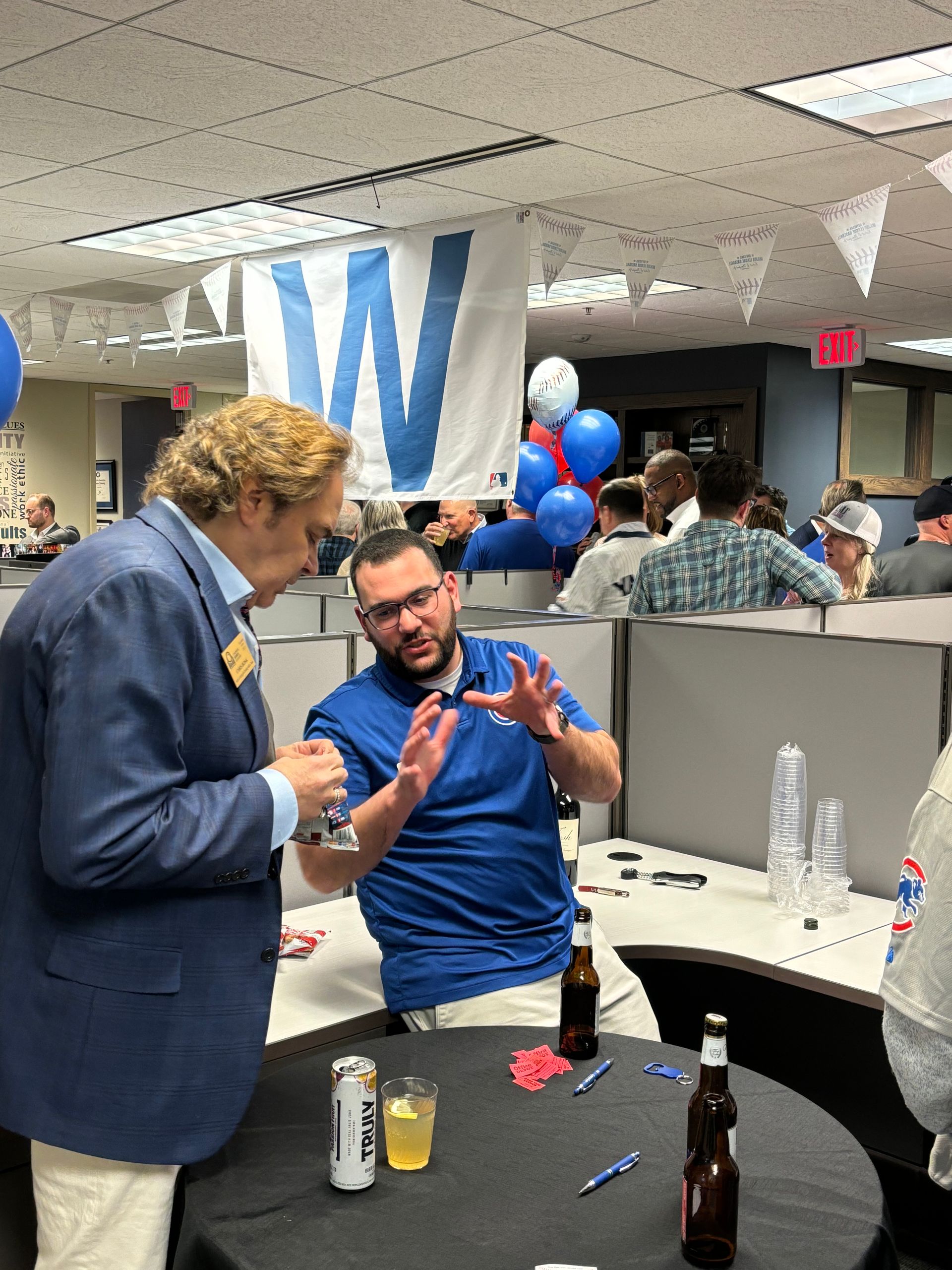 A man standing next to a man sitting at a table