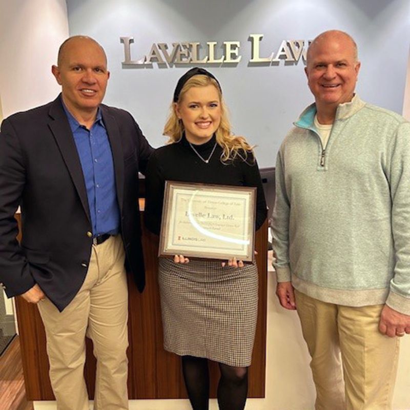 Three people standing in front of a sign that says lavelle law