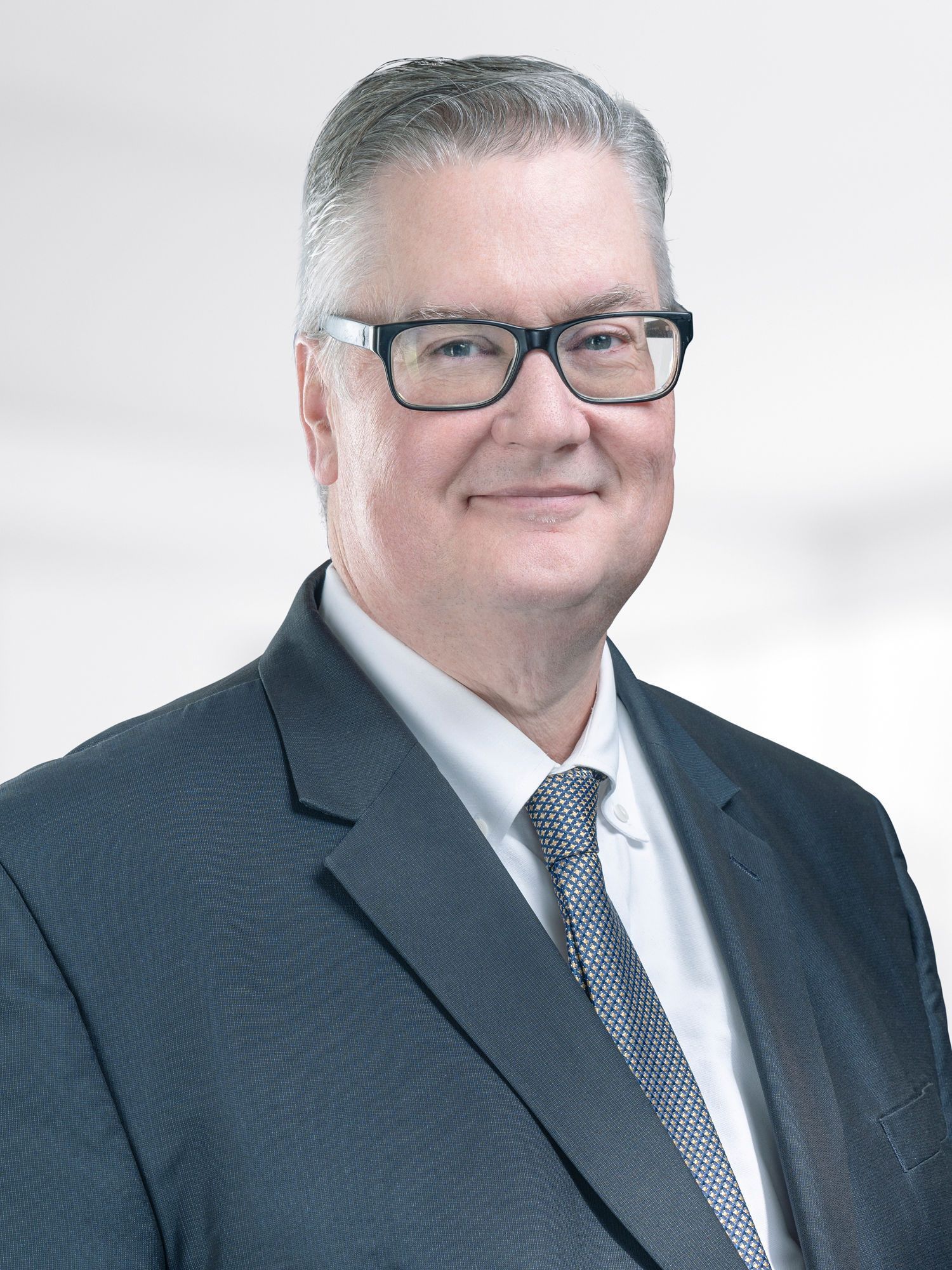 A man in a suit and tie is wearing glasses.