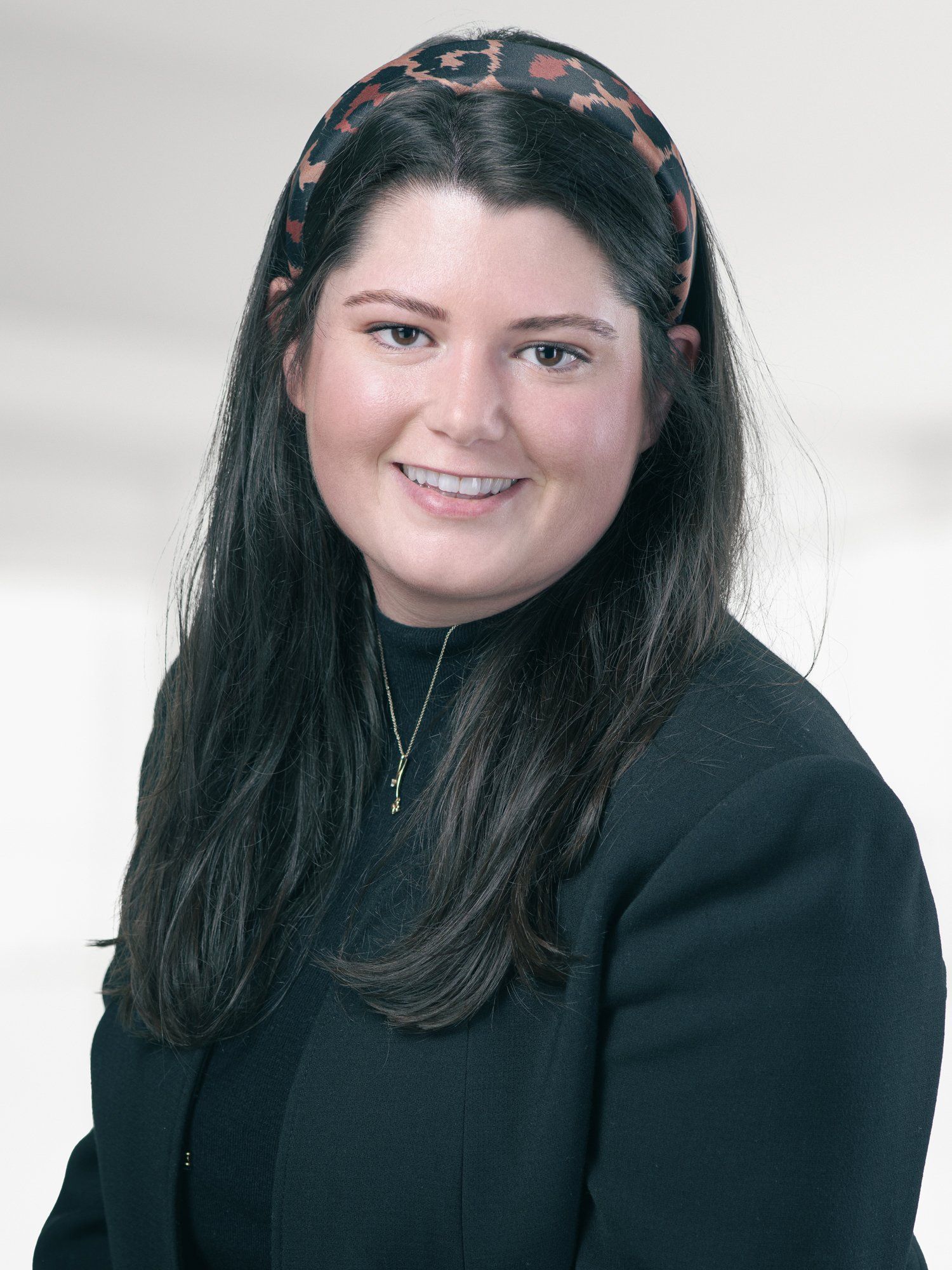 A woman wearing a headband and a black jacket is smiling for the camera.