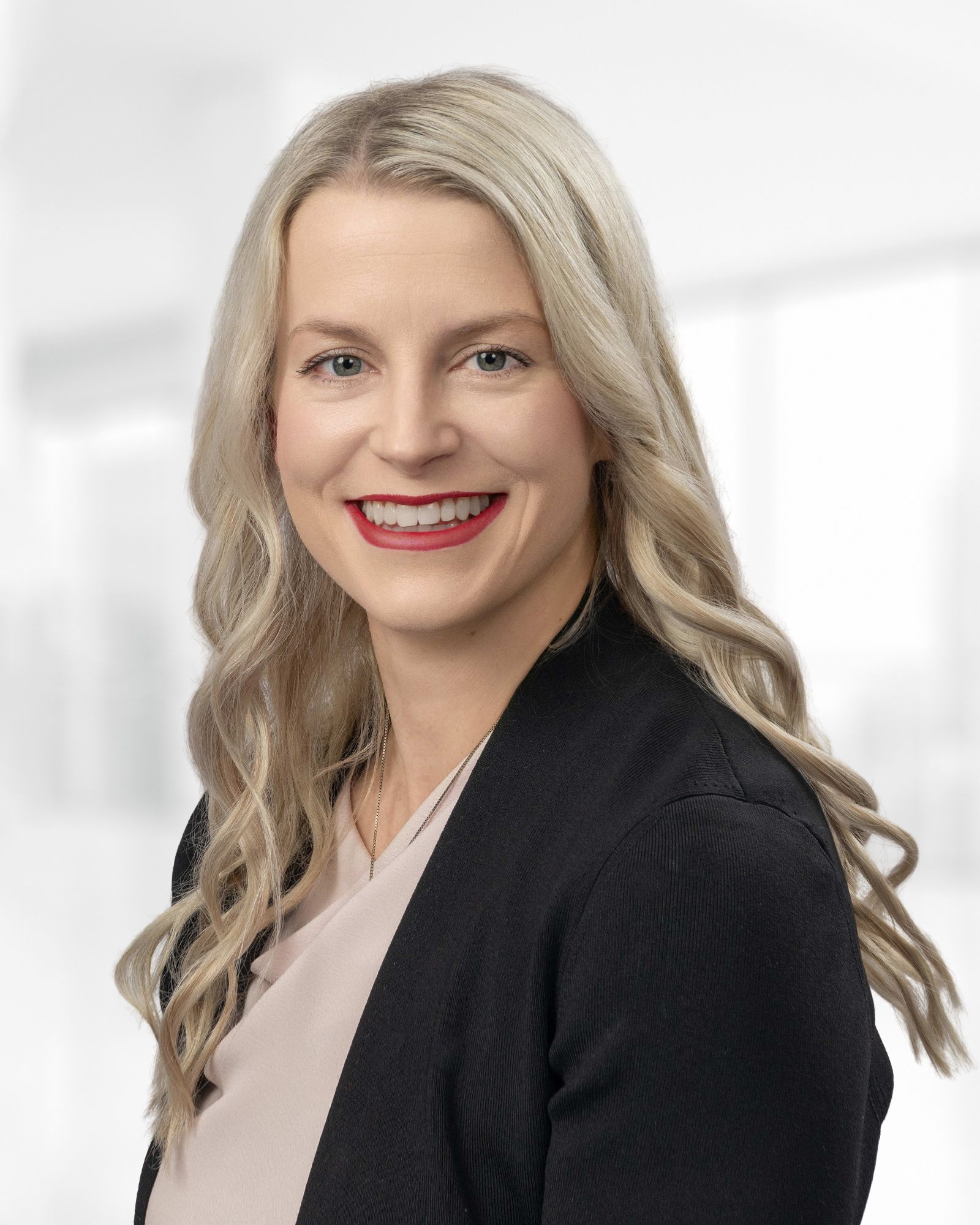 A woman smiling wearing a professional suit.