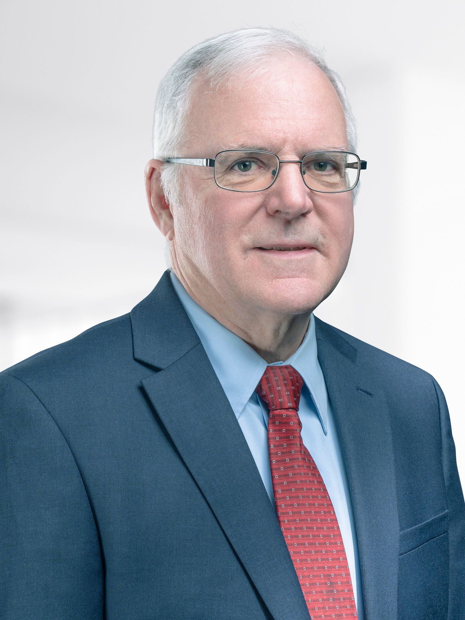 A man in a suit and tie is wearing glasses.