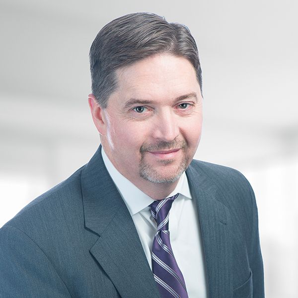 A man in a suit and tie is smiling for the camera.