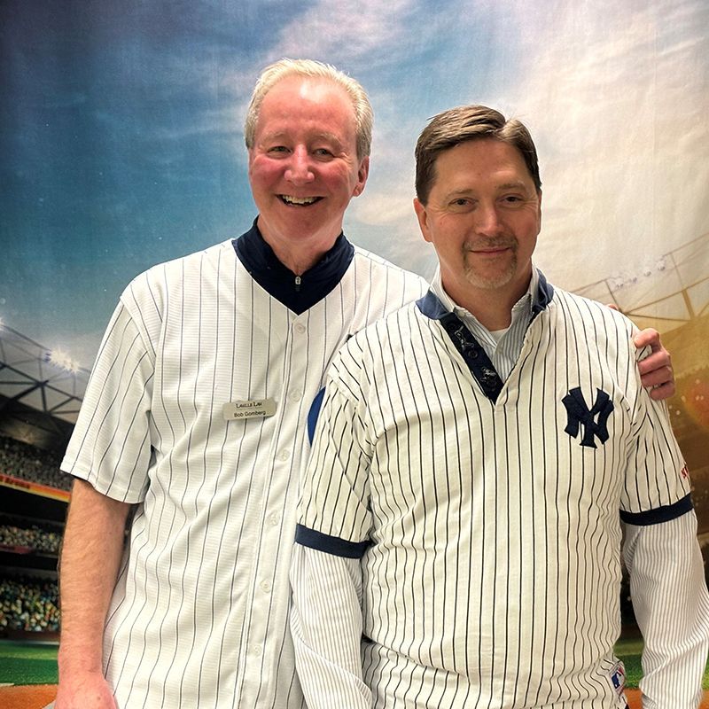 Two men wearing ny yankees jerseys pose for a picture