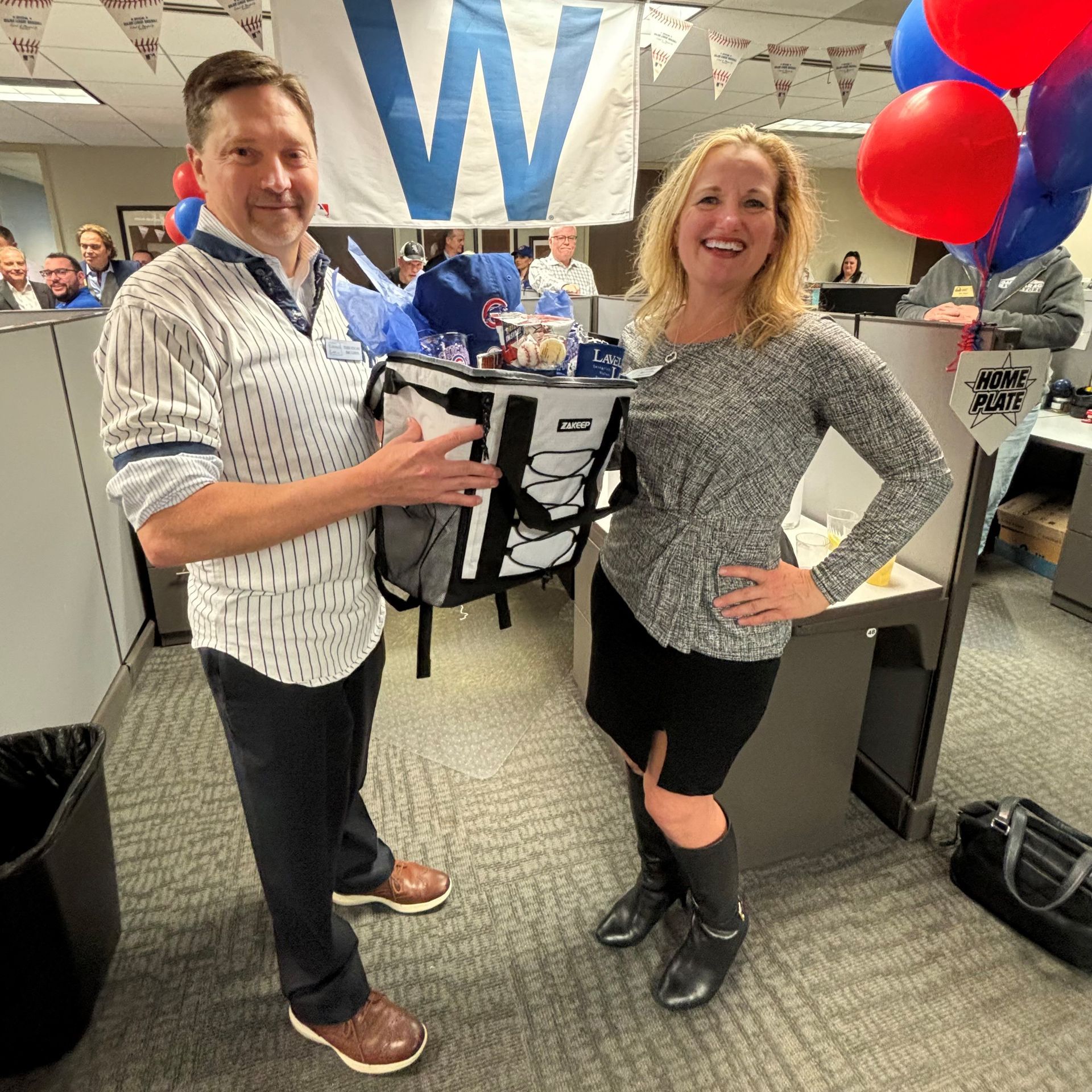 A man and a woman are standing next to each other in an office cubicle.