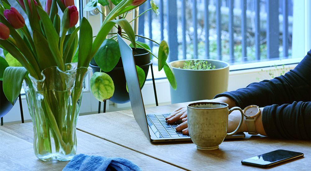 A person is sitting at a table with a laptop and a cup of coffee.
