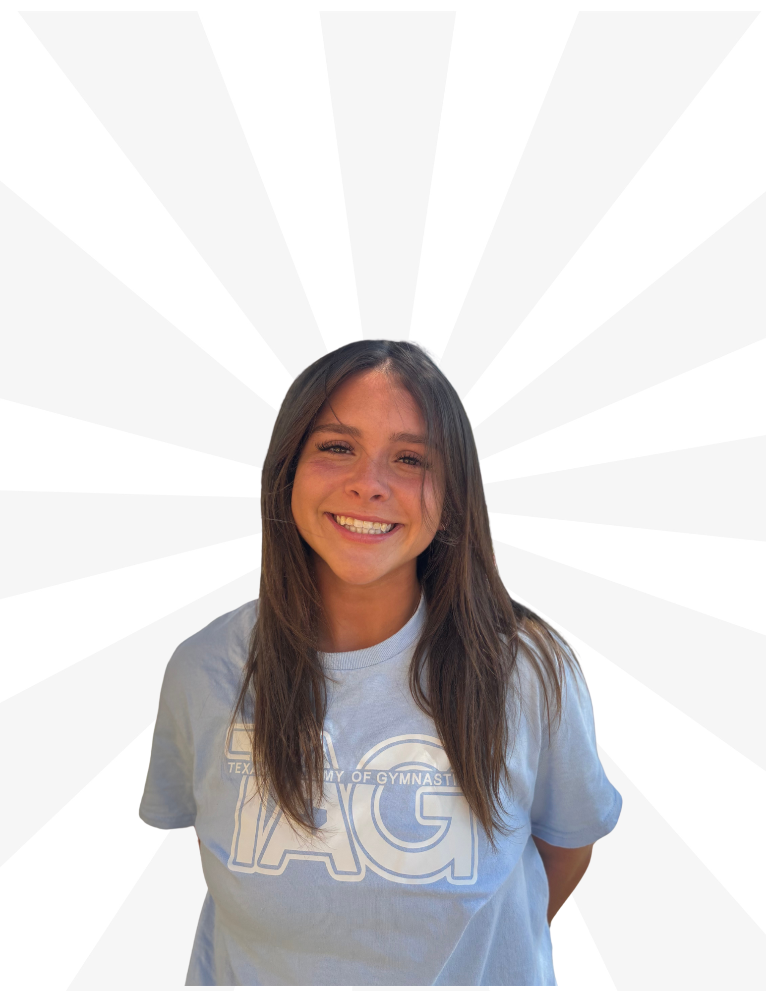 A smiling person with long dark hair, wearing a light blue t-shirt with large white letters, against a white sunburst background.