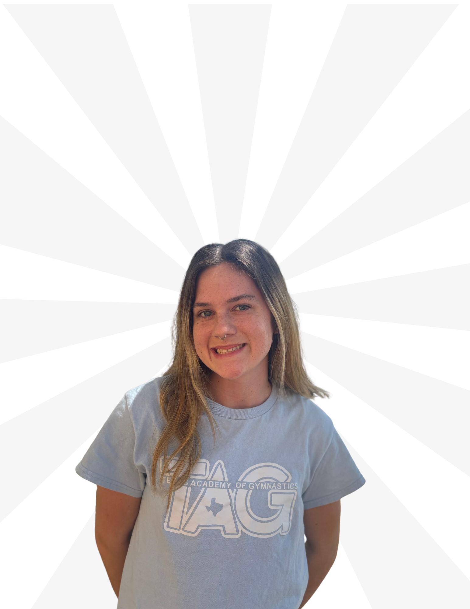 A smiling person wearing a light blue t-shirt with white text stands against a light gray radial burst background.