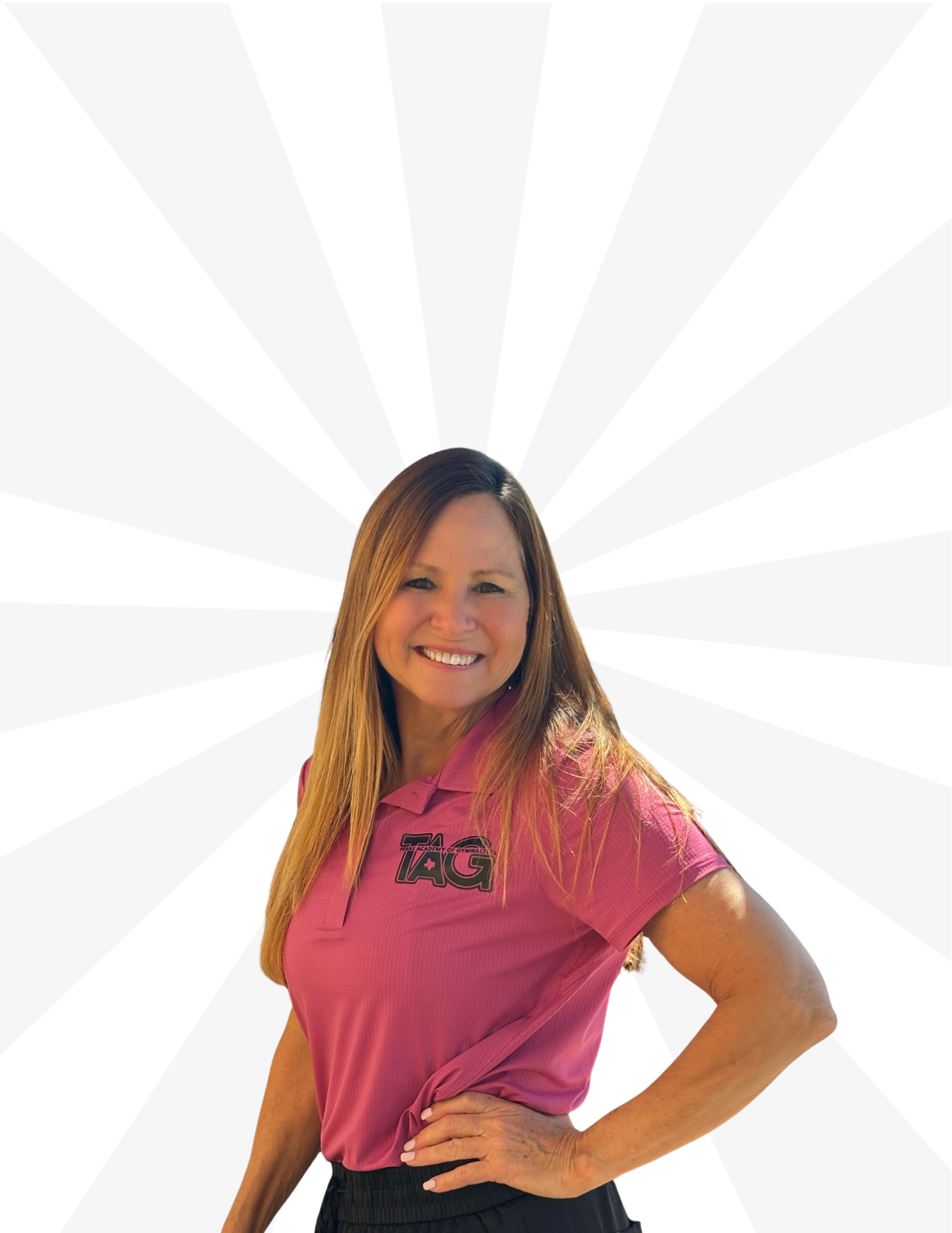 Smiling person with long hair wearing a pink polo shirt and dark pants, posed against a white radial striped background.