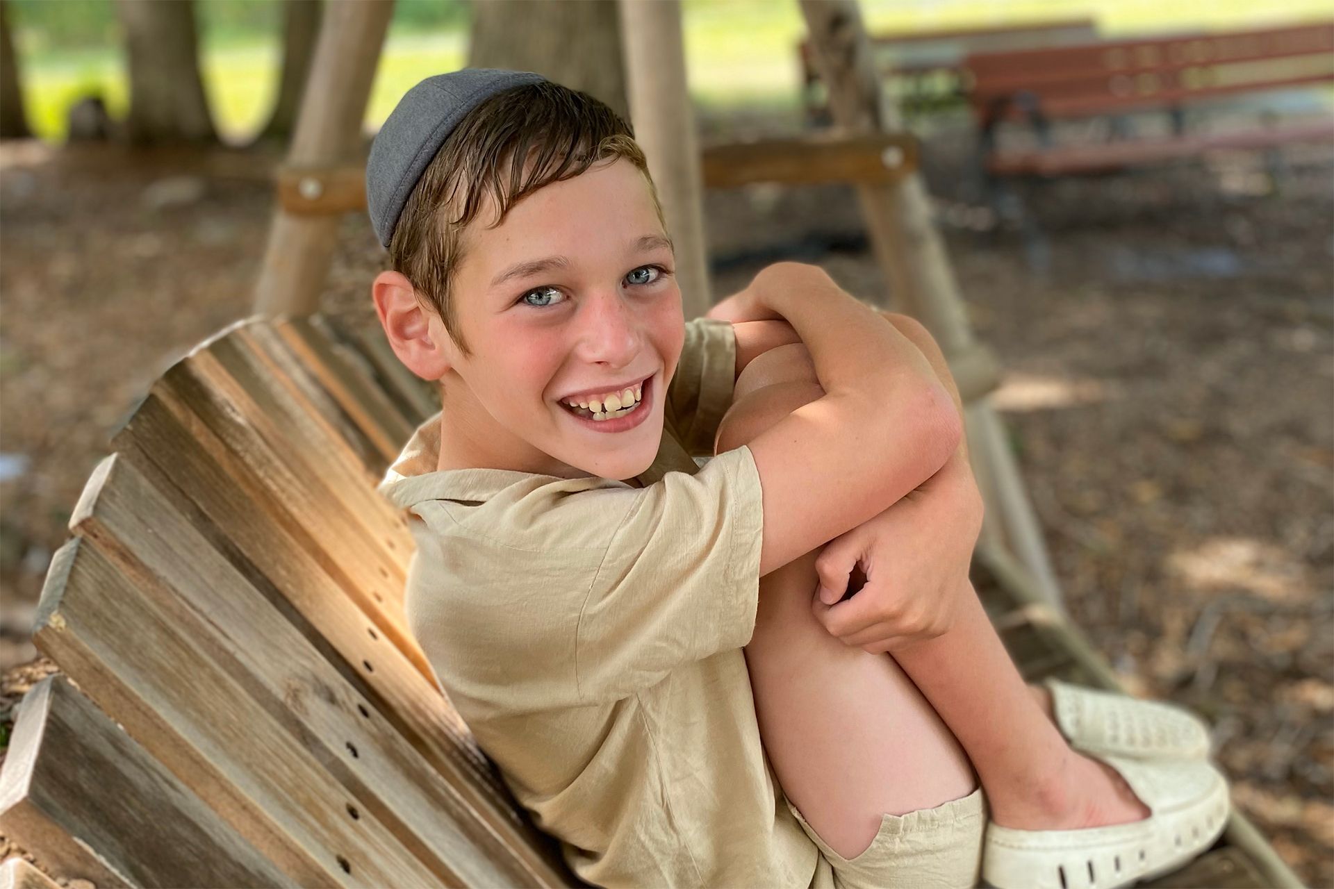 A young boy sitting on a bench and smiling.
