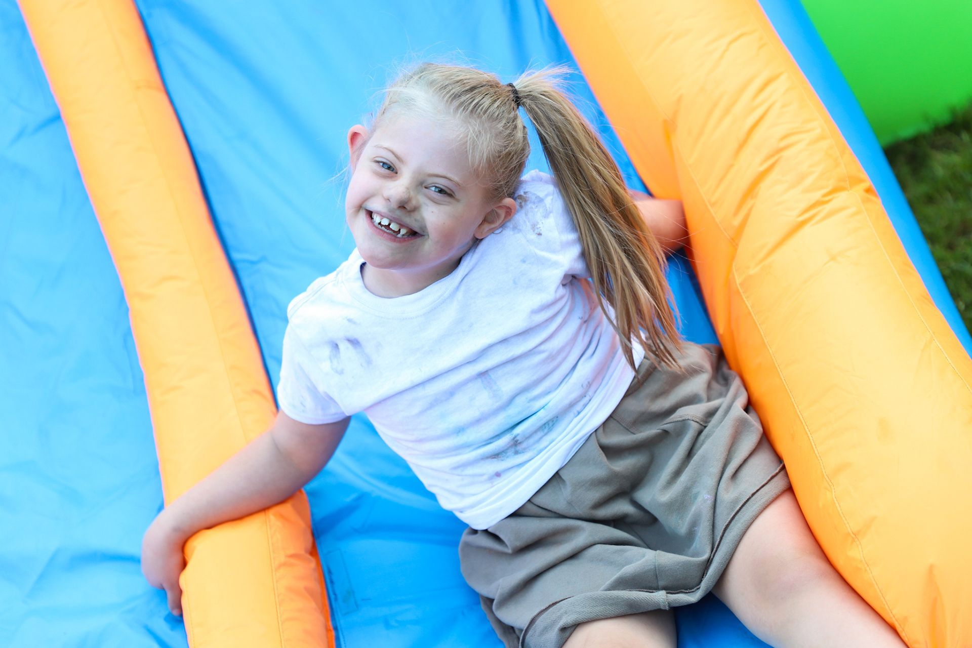 A young girl is on a moon bounce and smiling.