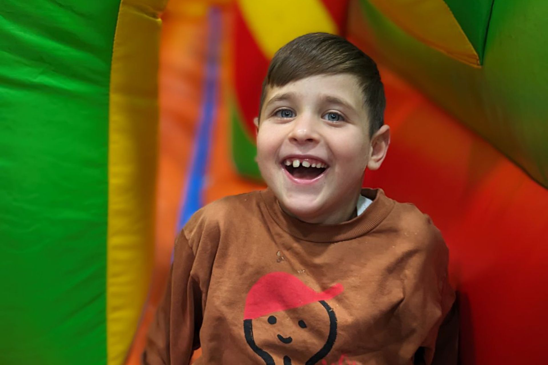 A young boy is in a bouncy house and smiling.