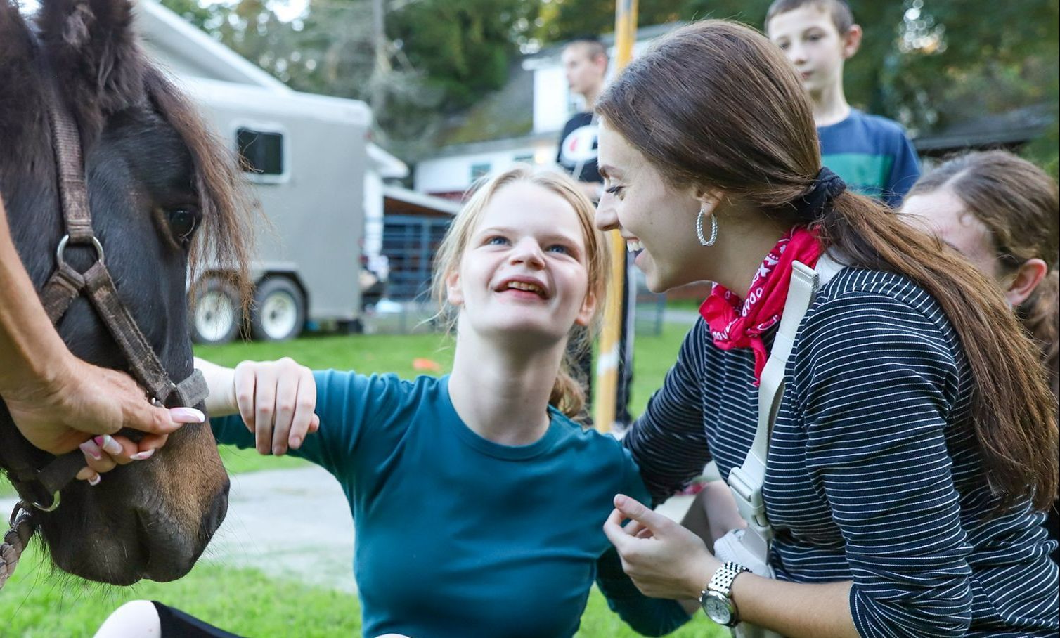 A women and a girl are petting a horse.