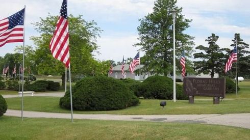 American flags along a landscaped road with trees, shrubs
