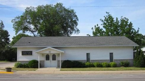 Single-story white building with a centered double door, black shutters