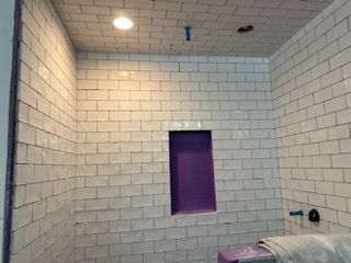 A bathroom with white tiles and a purple niche.