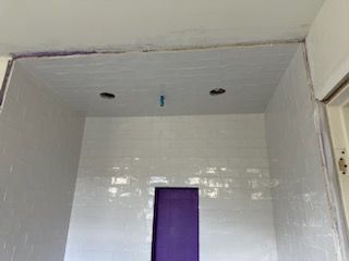 A bathroom with white tiles and a purple door.