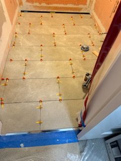 A tile floor is being installed in a bathroom.