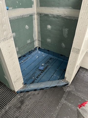 A bathroom under construction with a blue mat on the floor.
