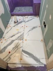 A bathroom floor with marble tiles being installed.