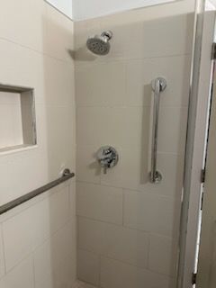 A shower with a hand rail and a shower head.