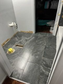 A bathroom with a tiled floor and a hole in the floor.