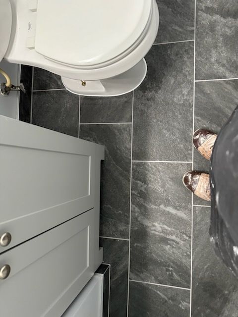 A person standing next to a toilet in a bathroom