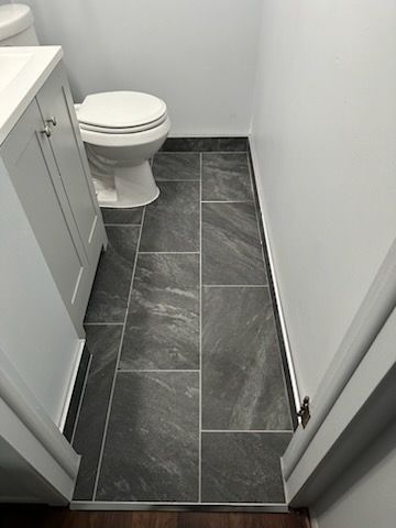 A bathroom with a toilet , sink , and tile floor.