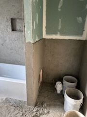 A bathroom under construction with buckets and a bathtub.