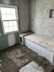 A bathroom under construction with a bathtub and a window.