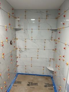 A bathroom with a lot of tiles on the wall and shelves.