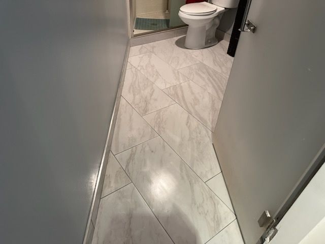 A bathroom with white tile floors and a toilet.