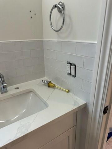 A bathroom with a sink and a towel ring on the wall.