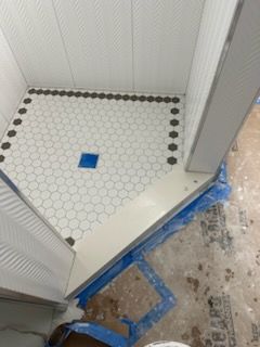 A bathroom with a tiled floor and a blue drain.