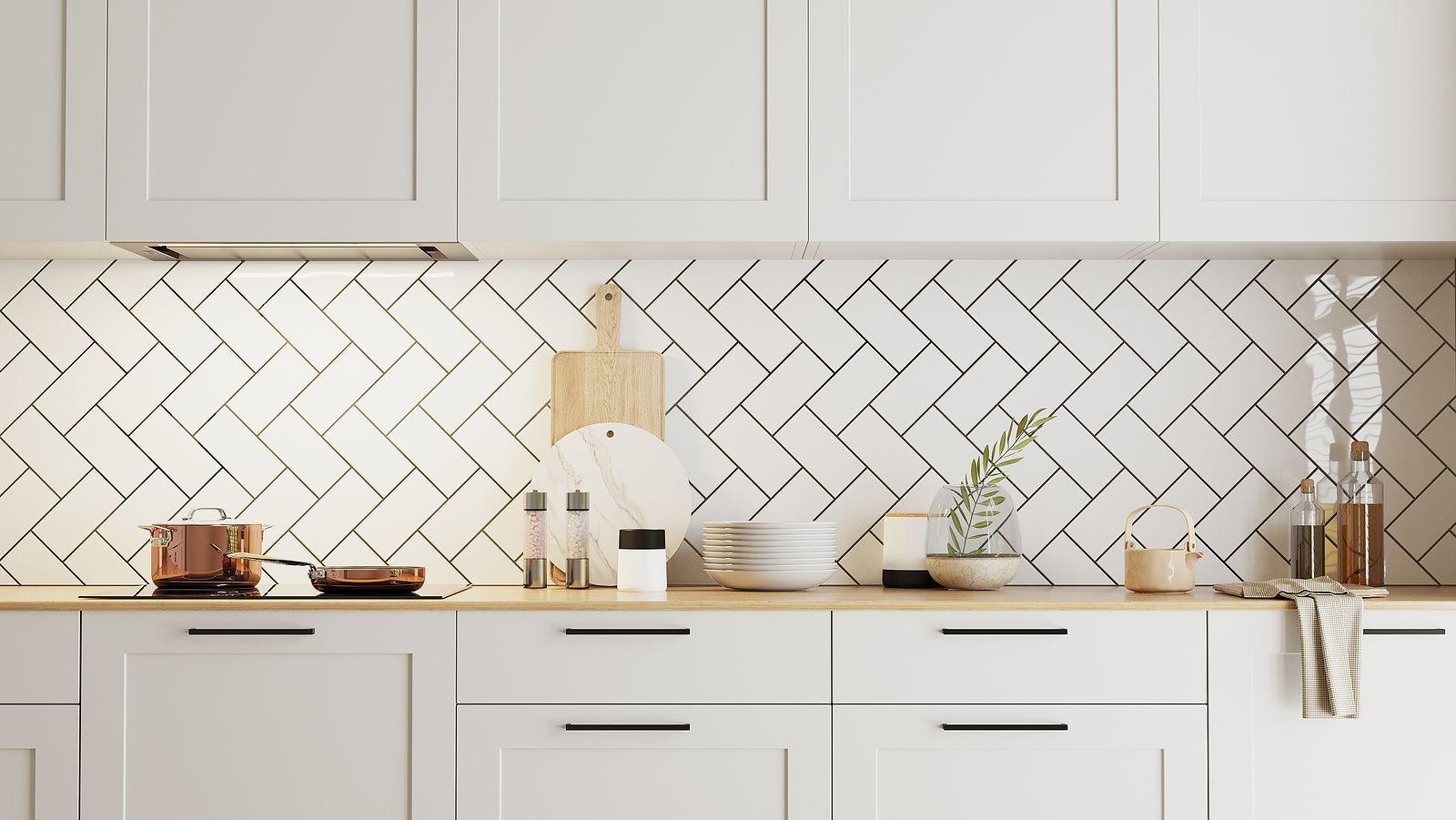 A kitchen with white cabinets and black handles and a herringbone tile backsplash.