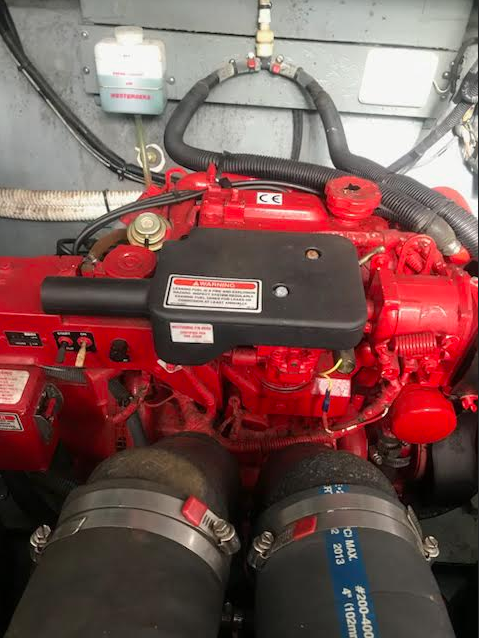 Red marine engine with black hoses and twin air filters in a machinery compartment