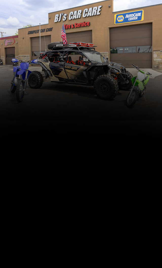 Off-road side-by-side vehicle parked outside Big O Car Care center with a tow truck nearby | BJ's Car Care
