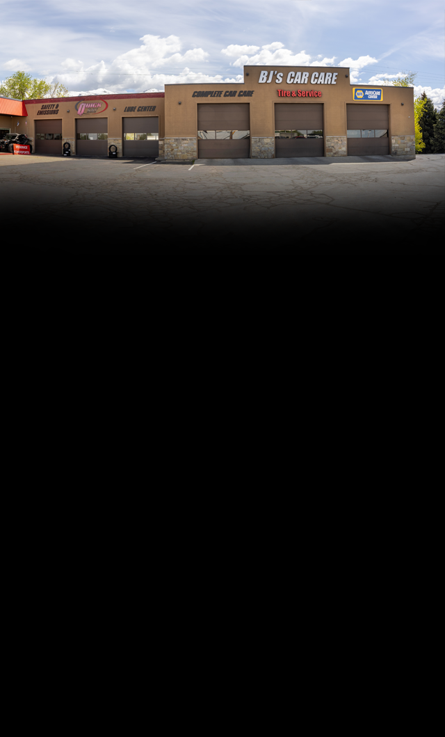 Strip mall storefronts with a tan facade and cloudy sky above | BJ's Car Care